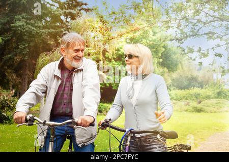 Middle aged couple riding bicycles in the park. Active lifestyle. in nature. Stock Photo