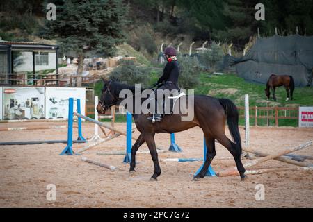 Stunning Images of Women Riding Horses to Jump over Obstacles. Woman jumping in the manege with a horse. Stock Photo
