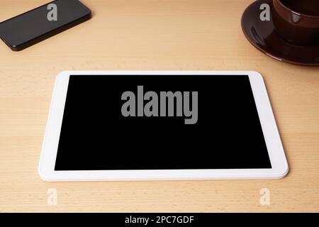 tablet computer with blank screen lying on desk with smartphone and coffee cup Stock Photo