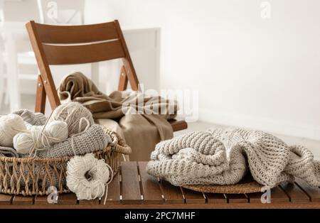 Basket with threads for knitting on a wooden bench in the interior of the room. Stock Photo