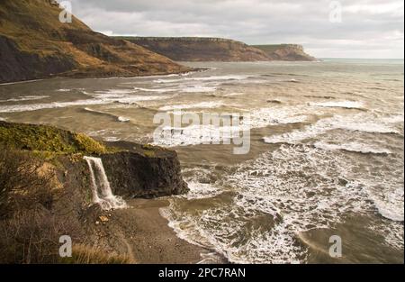View of coastline with waterfall flowing over hard shale to beach on coast with rough sea, freshwater steps, Dorset, England, United Kingdom Stock Photo