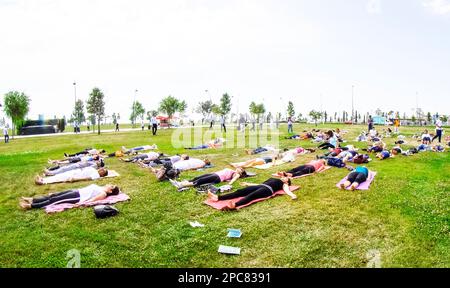 Baku, Azerbaijan, may 20, 2019: men and women practice yoga in a Park on a green glade. Stock Photo