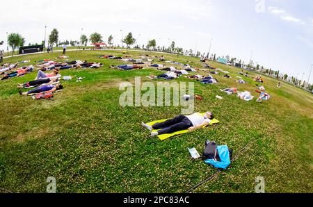 Baku, Azerbaijan, may 20, 2019: men and women practice yoga in a Park on a green glade. Stock Photo