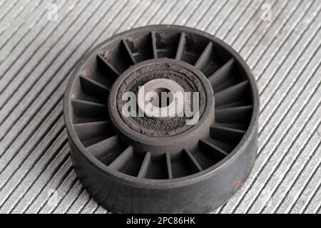 Old dirty car roller made of plastic and bearing on a gray background. Stock Photo