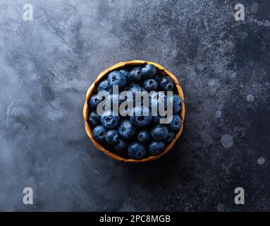 Fresh organic blueberry in mini basket on vintage dark table. Concept of healthy eating. Top view, copy space. Stock Photo