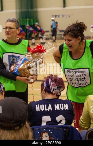 Two volunteers selling raffle tickets for a children's charity at a roller derby in Southend Stock Photo