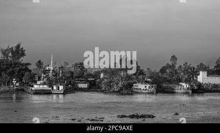 Boats and motorised barges lie pulled up on the banks of the Mekong river near Long Xuyen in the Mekong Delta, Vietnam. Stock Photo