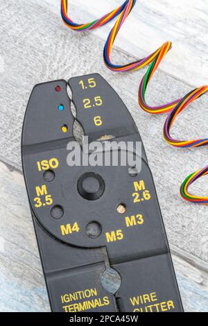 Close shot of Chinese-made unbranded wire stripper & wire cutter for 26-10AWG wire (see Notes) with coils of fine multi-colour electrical wire. Stock Photo