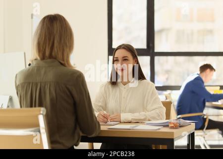 Business woman talking to client and making notes on documents in office. Stock Photo