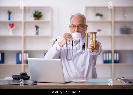 Old doctor in time management concept Stock Photo