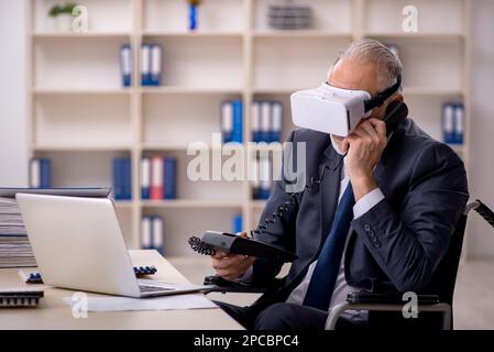 Old leg injured businessman employee wearing virtual glasses in the office Stock Photo