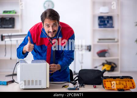 Young repairman repairing oven at workshop Stock Photo