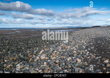 Waves lapping onto a stony beach off Bootle in Cumbria on the coast of the Irish Sea, looking towards the Sellafield Nuclear Waste Plant, Cumbria, UK. Stock Photo