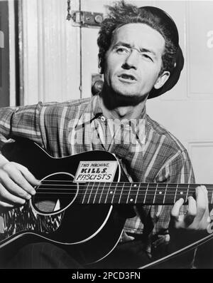 1943 , 8 march , USA :  The celebrated  american Country   singer  WOODY GUTHRIE (born Woodrow Wilson Guthrie , 1912 - 1967 ).  Photo by by Al Aumuller . Is best known as an American singer-songwriter and folk musician, whose musical legacy includes hundreds of political, traditional and children's songs, ballads and improvised works. He frequently performed with the slogan 'This Machine Kills Fascists' displayed on his guitar. His best known song is probably ' This Land Is Your Land '- CHITARRA - chitarrista - guitarist - MUSIC - ROCK - MUSICA LEGGERA - portrait - ritratto  - musicista - musi Stock Photo