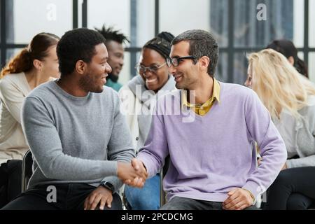 Happy multiethnic employees having fun while discussing project, sharing ideas, informal brainstorming sitting on chairs Stock Photo