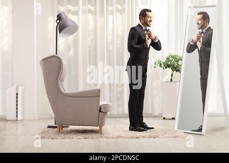 Full length profile shot of a young elegant man getting ready in front of a mirror at home Stock Photo