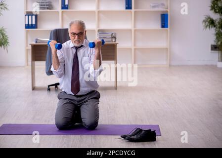 Old employee doing sport exercises during break Stock Photo