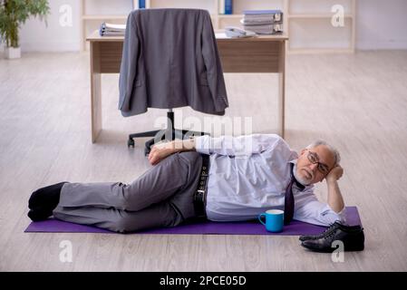 Old employee doing sport exercises during break Stock Photo