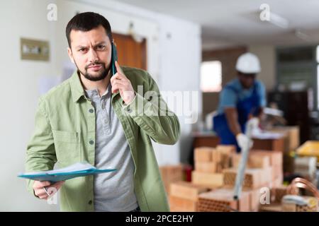 Construction manager with paper folder having telephone conversation Stock Photo