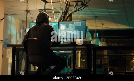 Female thief planning cyberwarfare and hacktivism at night, trying to break server firewall for cryptojacking or espionage. Criminal hacking network system on computer, anonymous. Stock Photo