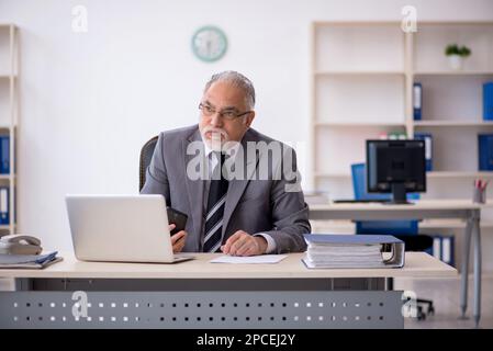 Aged male employee sitting at workplace Stock Photo