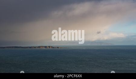 Sunlight illuminates vast seascape of Rathlin Island through a break in storm clouds off the Antrim Coast in Northern Ireland Stock Photo