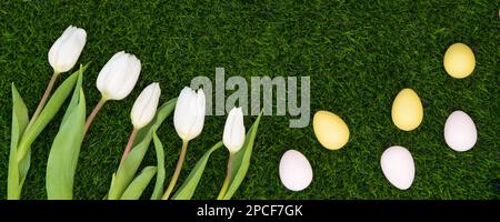 Easter color eggs with bouquet of tulips on green grass. Happy easter. Banner Stock Photo
