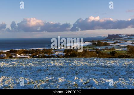 Snow-covered grass and fields in early morning light along the Antrim Coast in Ballycastle, Northern Ireland Stock Photo