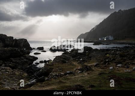 Sunlight breaking through dramatic storm clouds and rain along Northern Ireland's Antrim Coast Stock Photo