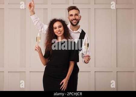 Happy couple with glasses of sparkling wine celebrating New Year indoors Stock Photo