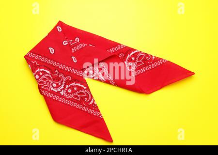 Folded red bandana with paisley pattern on yellow background, top view Stock Photo