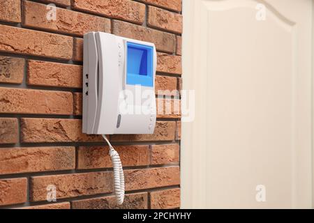 Modern intercom system with handset on red brick wall indoors, space for text Stock Photo