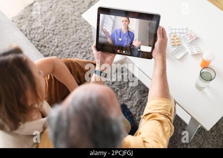 Using eHealth and telemedicine services at home. Senior couple using digital tablet having video call with online doctor Stock Photo