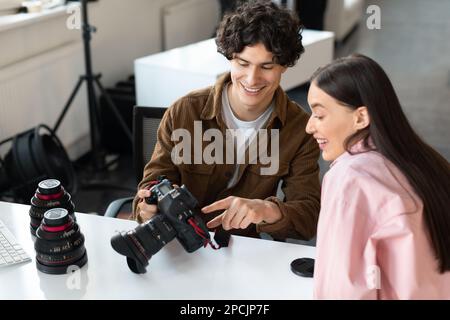 Male photographer and woman model discussing photos with camera, choosing images from photoshoot Stock Photo