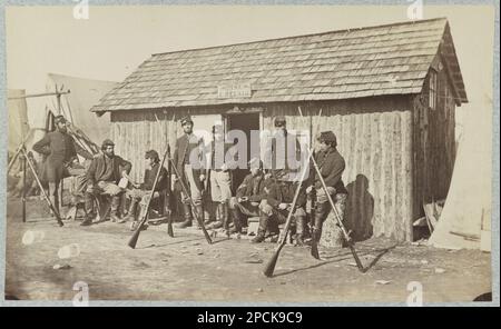 Soldiers outside a log cabin winter quarters, identified as 'Pine Cottage'. Title devised by library staff, See also: LOT 4172, no. 18, Gift; Col. Godwin Ordway; 1948. United States, History, Civil War, 1861-1865. Stock Photo