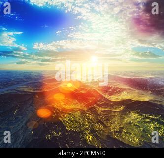 Sunrise or sunset over choppy, rough water and lens flare Stock Photo