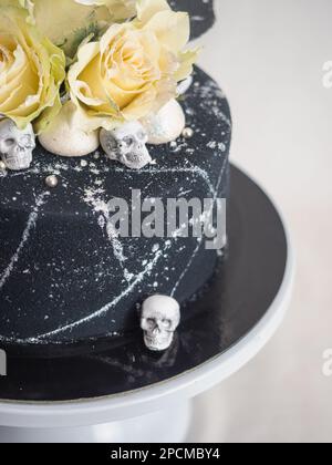 birthday black airbrush painted frosted icing cake, two real roses silver sprayed and edible chocolate skull toppers and silver brush strokes Stock Photo