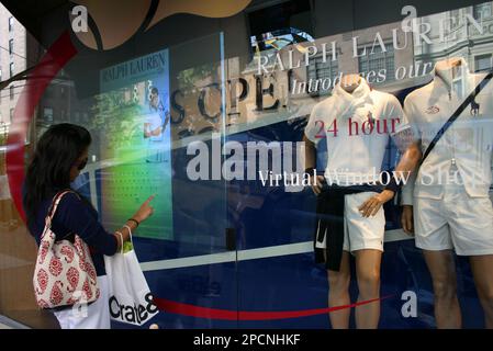A passerby tests a new interactive holographic screen on a Polo Ralph Lauren  store window that allows people to buy shirts, skirts and pants from the  company's U.S. Open tennis clothing line