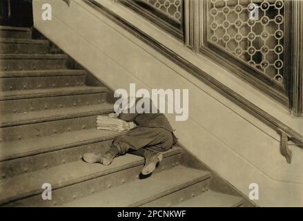 1912 , november , Jersey City, New Jersey, USA  : Newsboy asleep on stairs with papers - NEWSBOYS  , Photos by LEWIS HINE ( 1874 - 1940 ) -  - NEWSBOYS  - BAMBINI -- LAVORATORI - BAMBINO - CHILDREN WORKERS - FACTORY - CHILDHOOD - INFANZIA - LAVORO MINORILE - LAVORO - WORK - LAVORATORE - WORKER - OPERAIO -  CLASSE OPERAIA LAVORATRICE - WORKING CLASS - OPERAI - LAVORATORI - LAVORO - STATI UNITI d' AMERICA - FOTO STORICHE - HISTORY - portrait - ritratto  -  TEMPI MODERNI - MODERN TIMES  - hat - cappello - TURNO DI LAVORO - GIORNALAIO - GIORNALAI - STRILLONI - VENDITORI DI GIORNALI QUOTIDINI AMBUL Stock Photo