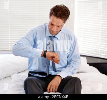 Time to get going. A businessman looking at his wristwatch after sleeping in too long. Stock Photo