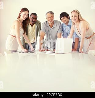 Dynamic business pros. Five colleagues using a laptop in the boardroom. Stock Photo