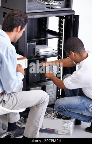 Finding the problem and fixing it. Two IT professionals working on a server. Stock Photo