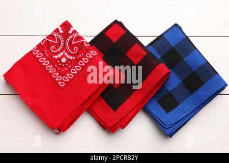 Folded bandanas with different patterns on white wooden table, flat lay Stock Photo