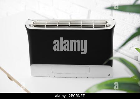 Air purifier on table near white brick wall, closeup Stock Photo