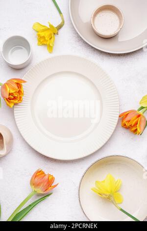 Composition with clean dishes and beautiful flowers on white grunge background Stock Photo