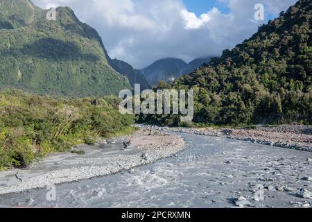 The fox river flows from the mountains and across the hilly forested landscape in the Westland district in the South island of Aotearoa New Zealand Stock Photo