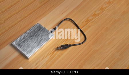 Top view of silver external hard drive laying on wooden background Stock Photo