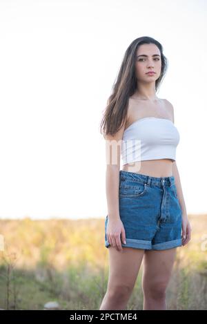 Beautiful young woman in denim shorts outdoors Stock Photo