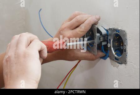 Electrican installing sockets, outlet plugs in the house. Stock Photo