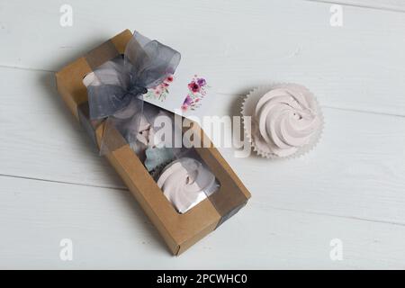 Homemade marshmallows in a cardboard box. Zephyr flowers. Box with transparent lid. Gift wrap. Tied with ribbon. Stock Photo